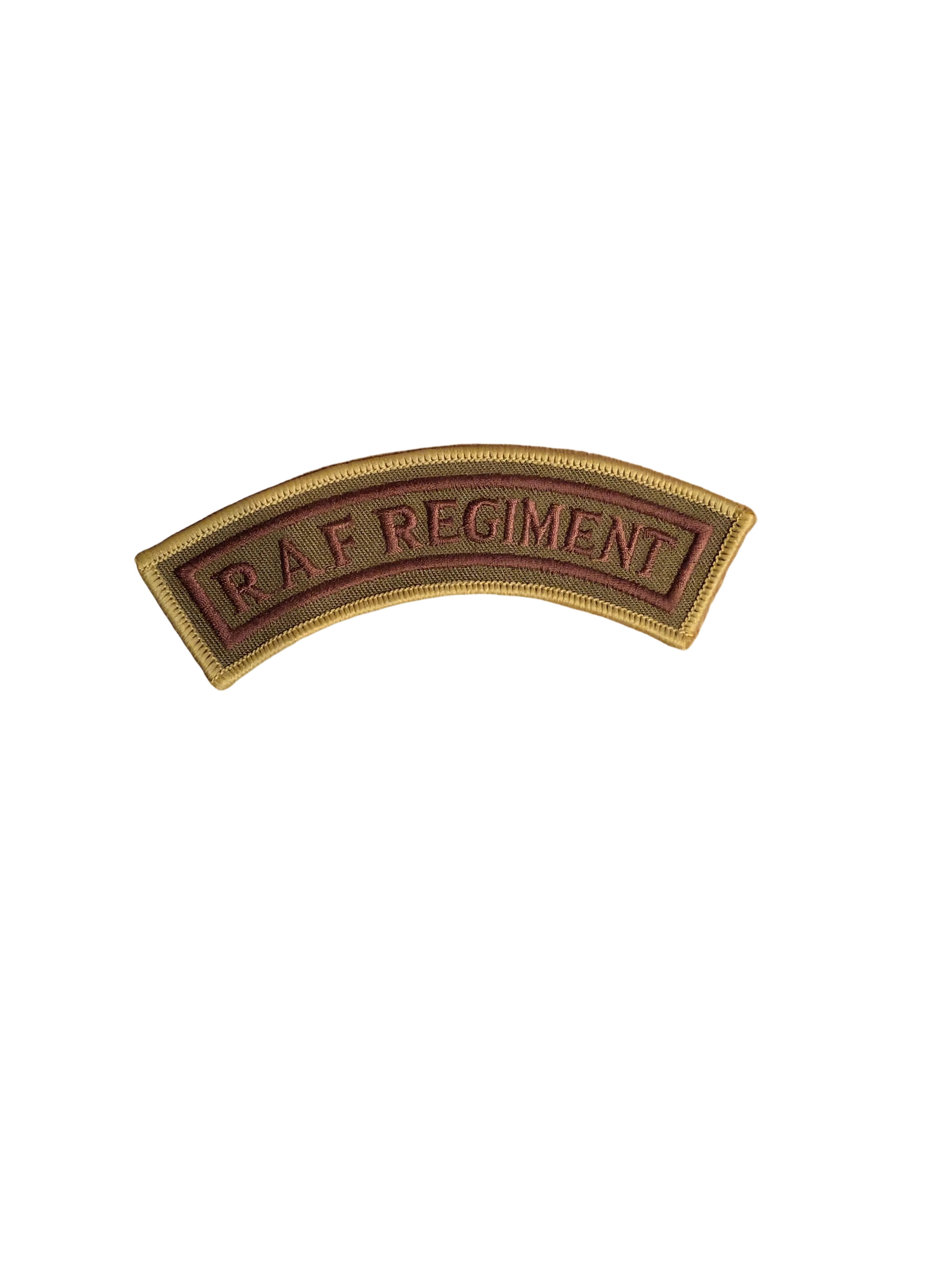 An embroidered military patch reading 'RAF REGIMENT' in gold lettering on a dark red background, bordered in gold, shown on a wooden surface next to a ruler.