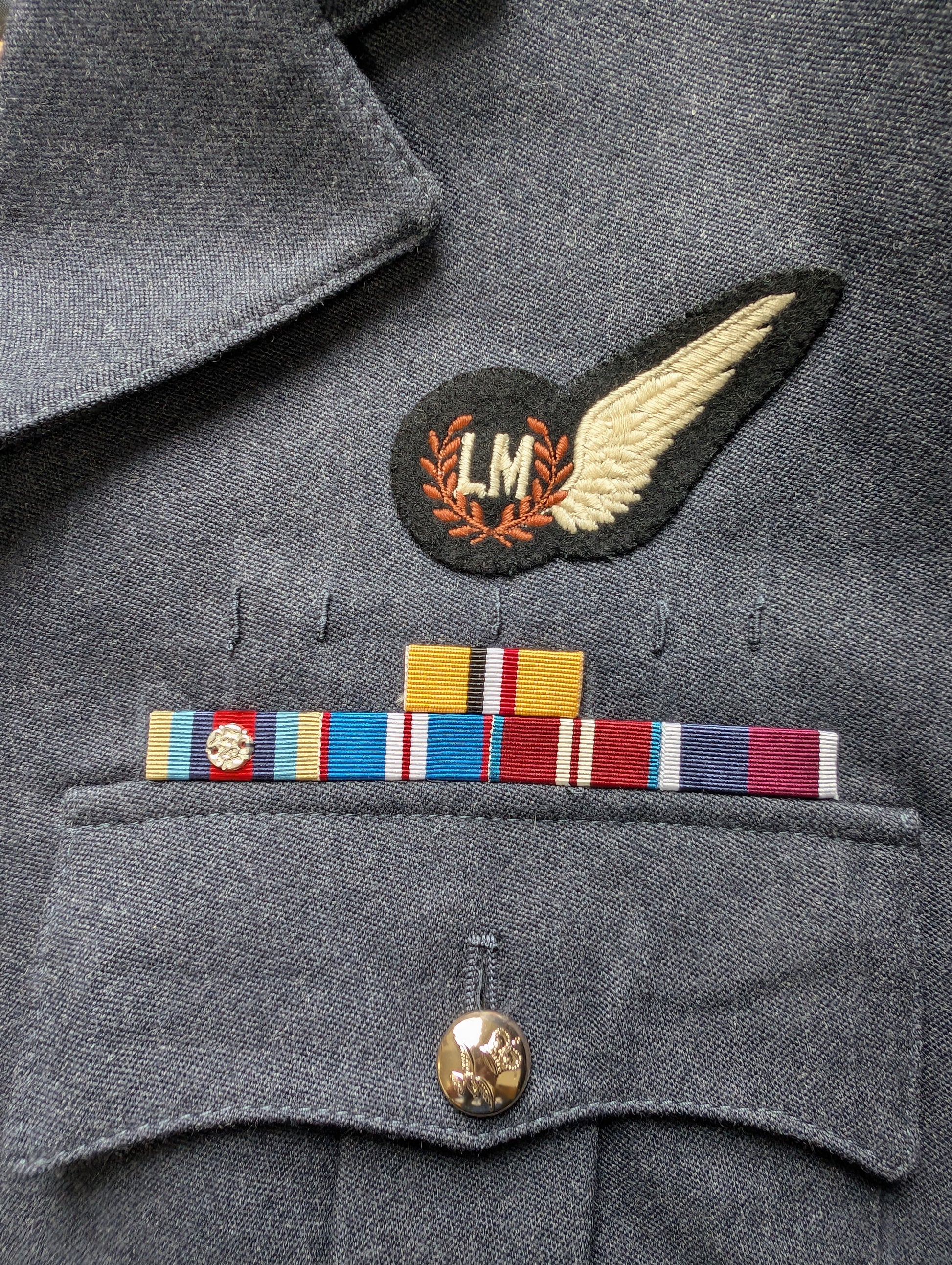 Close-up of a military uniform with insignia and ribbons on a gray background