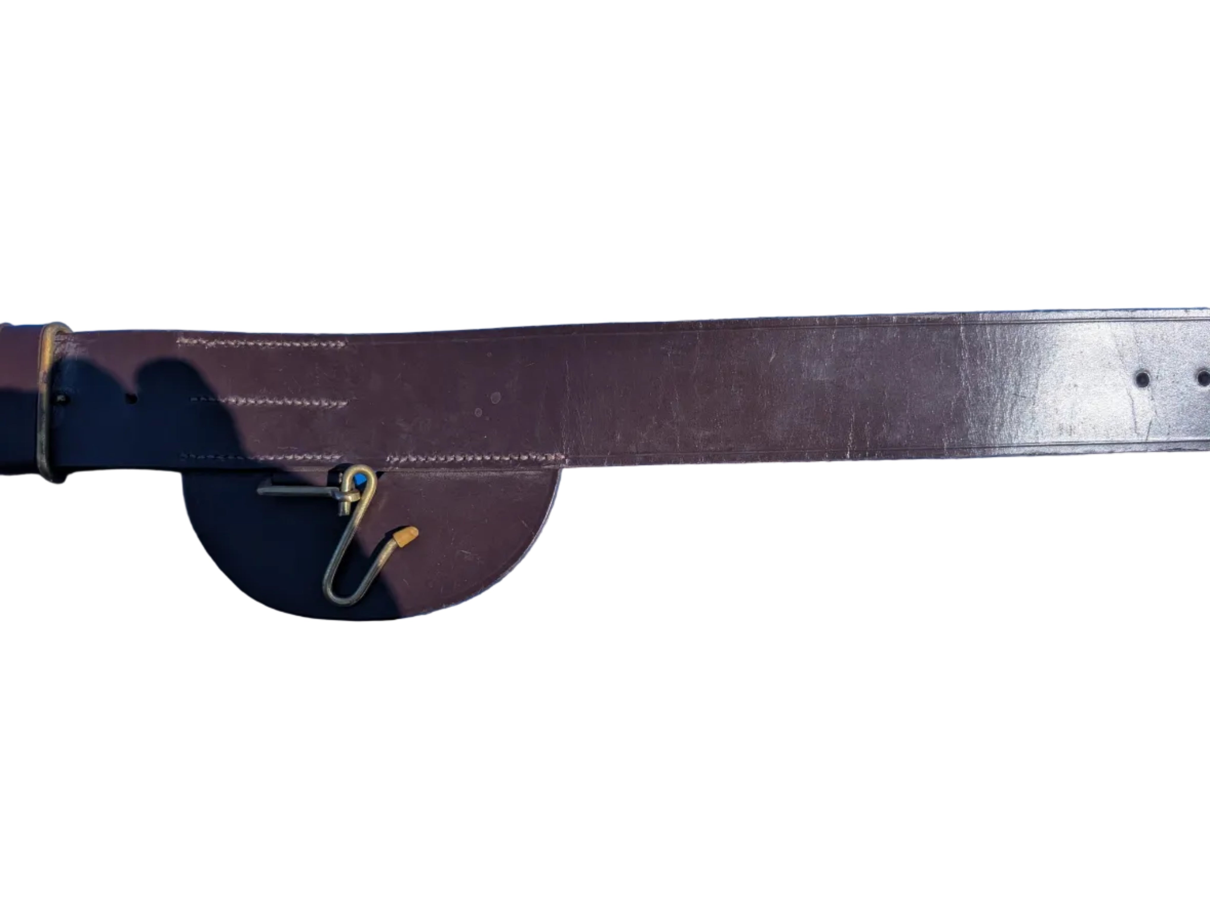 A close-up of a dark brown leather belt laid flat on a bright blue surface, with a small metal tool or clip near the buckle area and part of a shoe visible at the top left edge. British Army Infantry Brown Leather Sword Belt